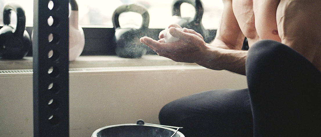 Hände mit Magnesia vor Kettlebells am Fenster